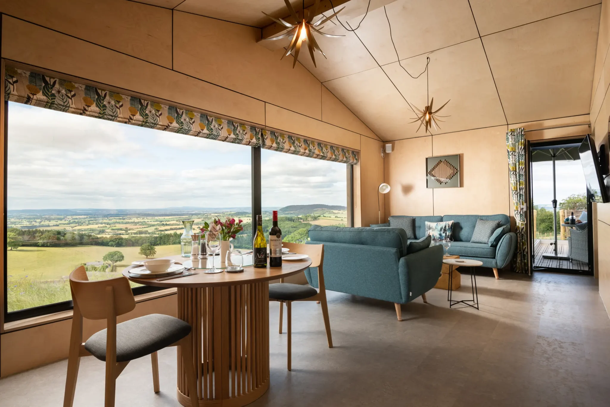 Open-plan kitchen, dining and sitting area showcasing the warm Scandinavian-inspired interior with views of multiple counties at Kestrel Retreat