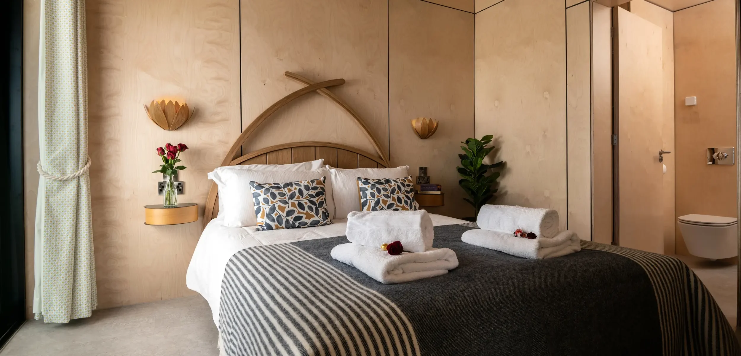 Beautiful oak bed and handmade oak light fittings complementing the warm Scandinavian interior at Kestrel Retreat