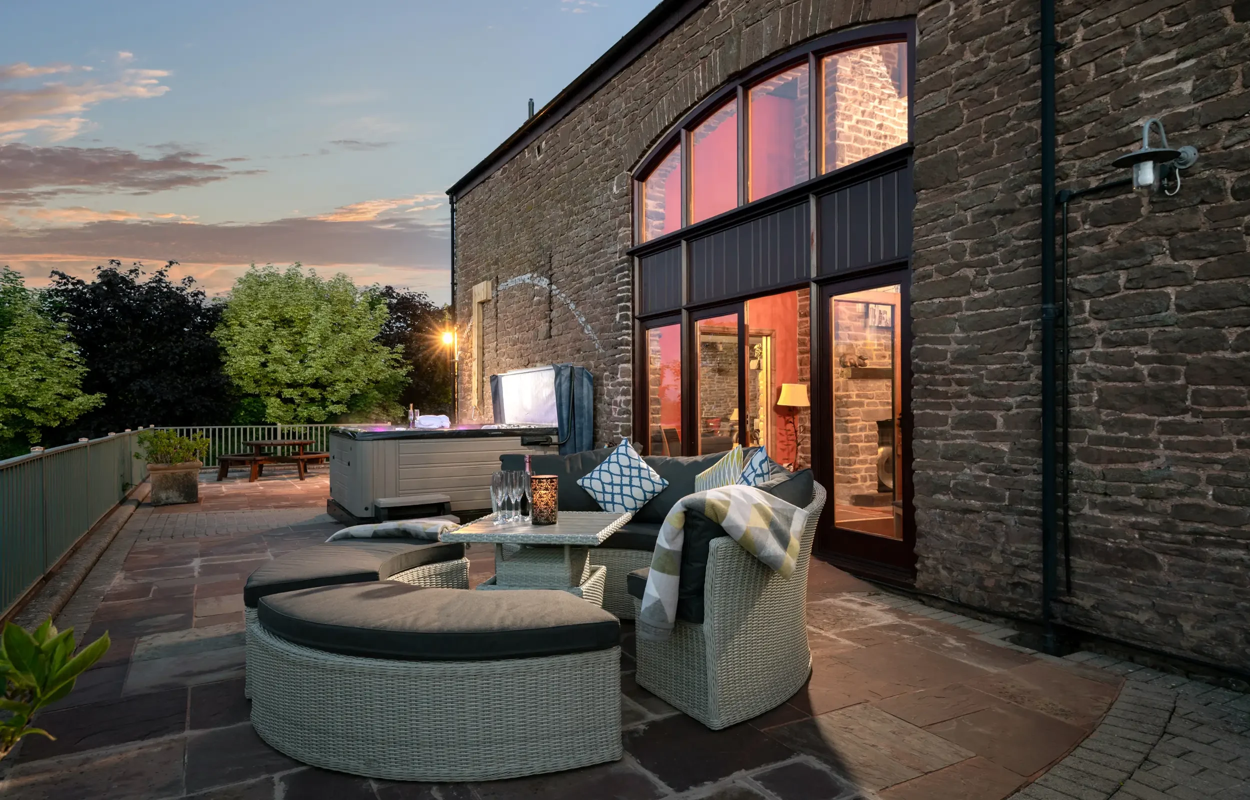 Dusk on patio with comfortable seating and hot tub, Penblaith Barn