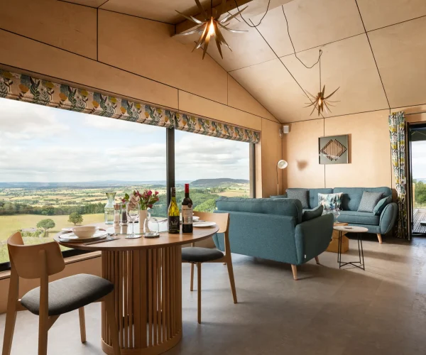 Open-plan kitchen, dining and sitting area showcasing the warm Scandinavian-inspired interior with views of multiple counties at Kestrel Retreat