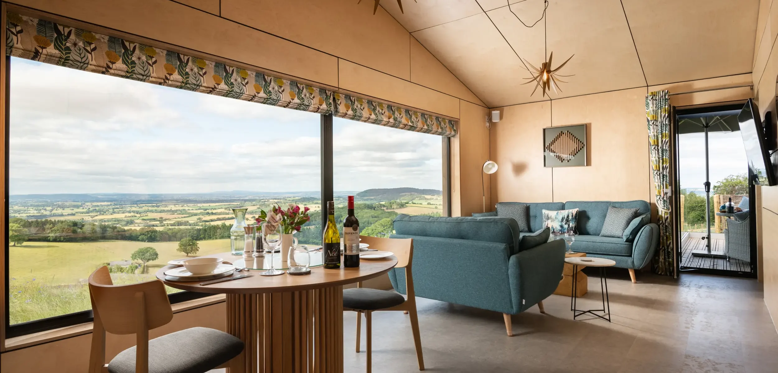 Open-plan kitchen, dining and sitting area showcasing the warm Scandinavian-inspired interior with views of multiple counties at Kestrel Retreat