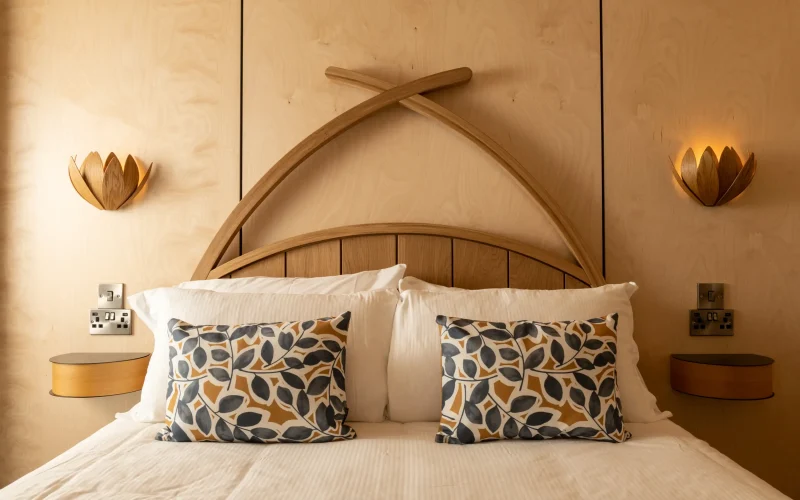 Close-up of the oak bed and handcrafted oak lighting in the Scandinavian-inspired bedroom at Kestrel Retreat