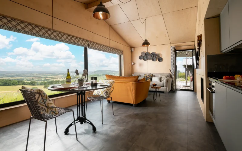 Open-plan kitchen, dining and sitting area at Peregrine Retreat with stunning views across many counties